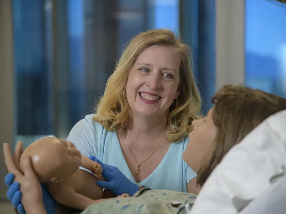 Physician midwife in simulated birthing suite delivering a simulated birth.