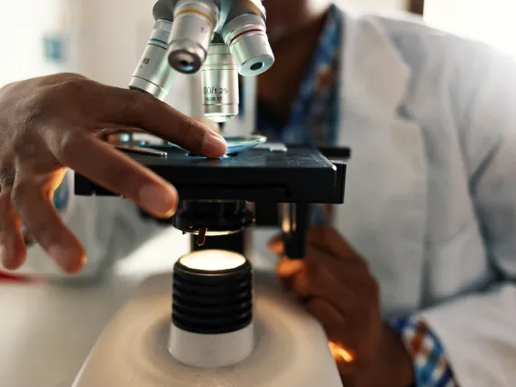 African-American researcher with microscope.