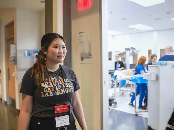 Nursing mid-wifery student walking past a birthing simulation room.