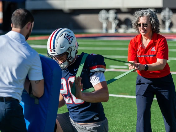 Physical therapist with football player on field