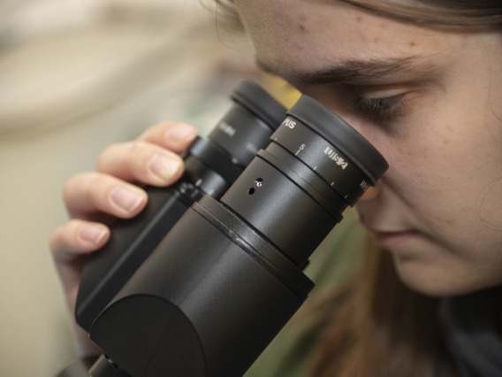 close up of a woman looking through a microscope