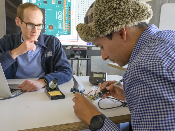 student soldering while instructor watches