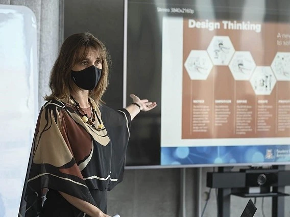 woman wearing a mask gesturing towards a presentation visual with her hand