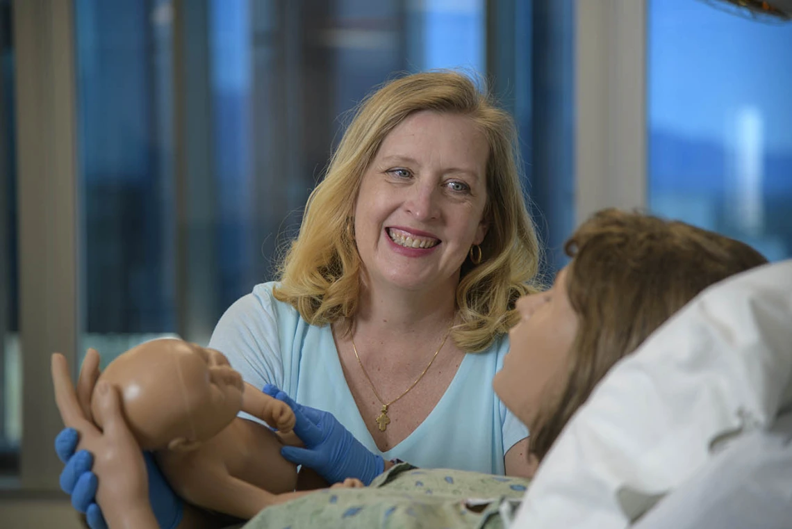 Physician midwife in simulated birthing suite delivering a simulated birth.