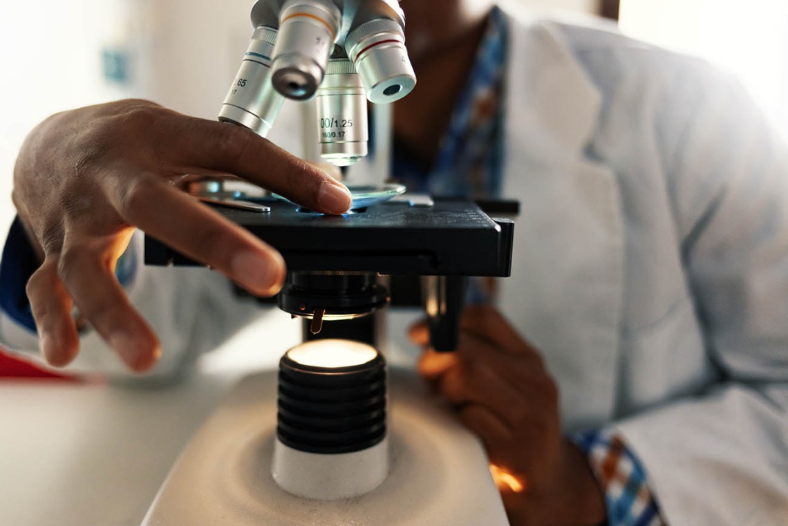 African-American researcher with microscope.