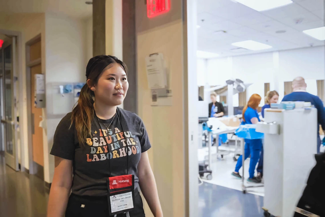 Nursing mid-wifery student walking past a birthing simulation room.