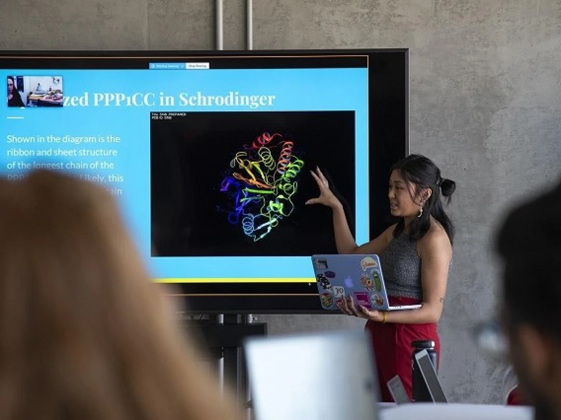 Student presenting while holding a laptop