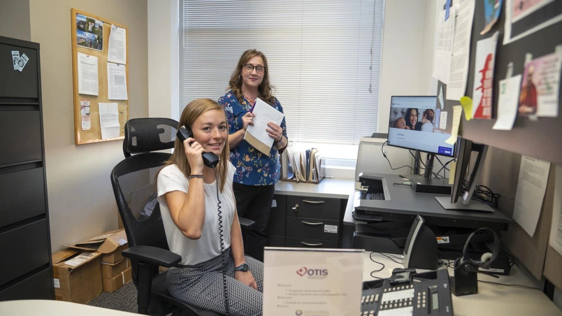 two women in office, one on phone