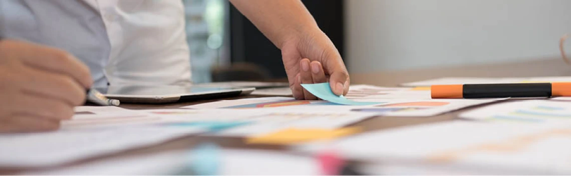 close up of hand placing a sticky note onto a board.