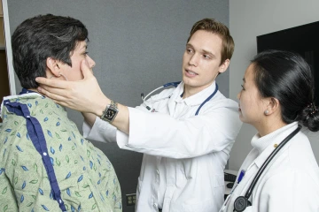 Male and female 3rd year med student examining a patient.