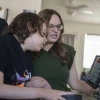 Mother and son in wheelchair looking at screen communication device