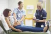 a pregnant lady is examined by young student midwife overseen by a senior nurse